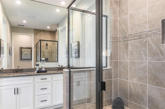 full bathroom featuring visible vents, double vanity, recessed lighting, a sink, and a shower stall