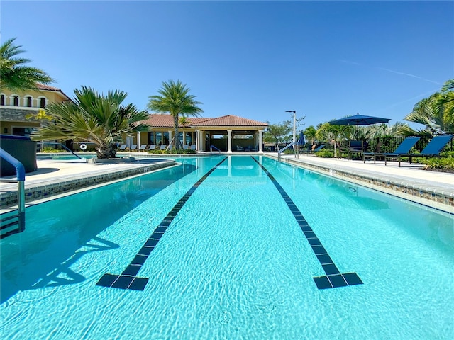 community pool with a patio area and fence