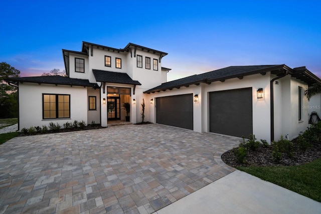 view of front facade with stucco siding, decorative driveway, and a garage