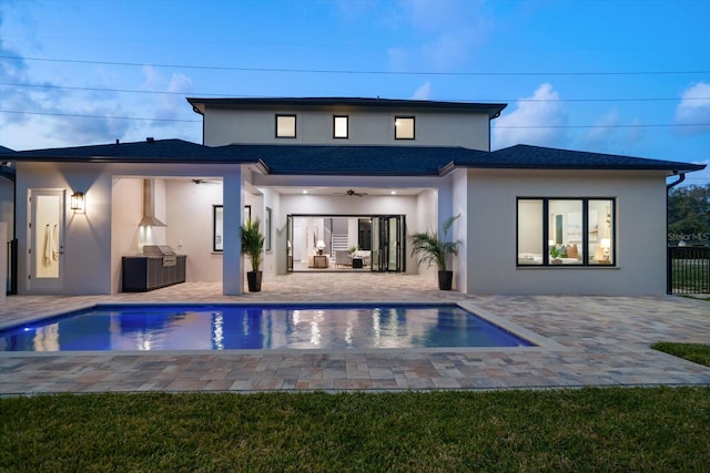 back of property with ceiling fan, a patio, an outdoor pool, and stucco siding