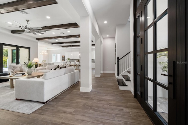 living area featuring visible vents, beam ceiling, dark wood-style flooring, baseboards, and stairs