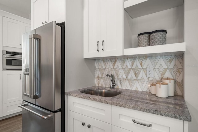 kitchen featuring stone counters, white cabinets, appliances with stainless steel finishes, and a sink