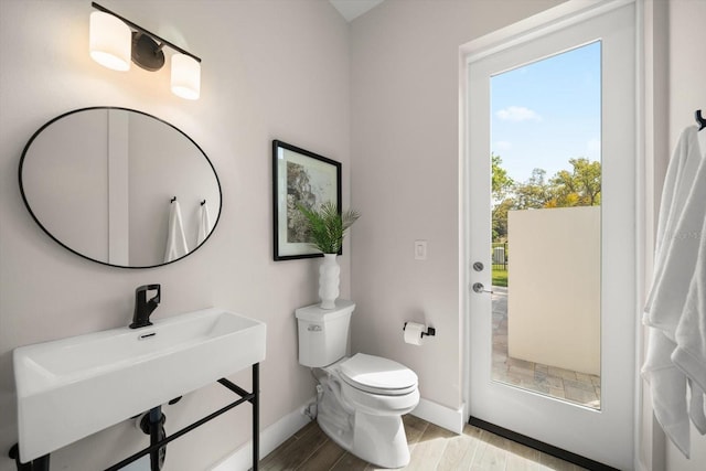 bathroom with a sink, toilet, baseboards, and wood finished floors