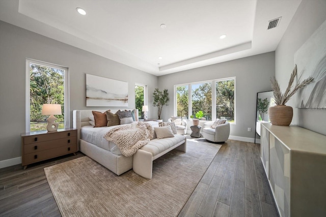 bedroom featuring wood finished floors, baseboards, visible vents, recessed lighting, and a raised ceiling