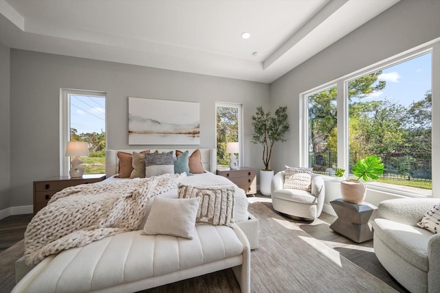 bedroom with recessed lighting, a raised ceiling, baseboards, and wood finished floors