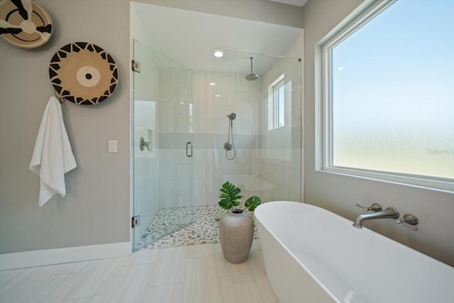 bathroom with baseboards, a freestanding bath, and a shower stall