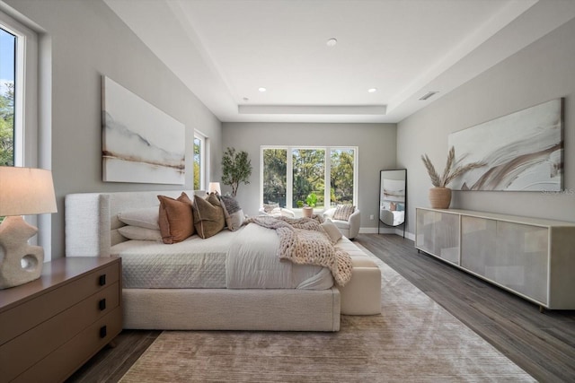 bedroom with wood finished floors, visible vents, baseboards, a tray ceiling, and recessed lighting