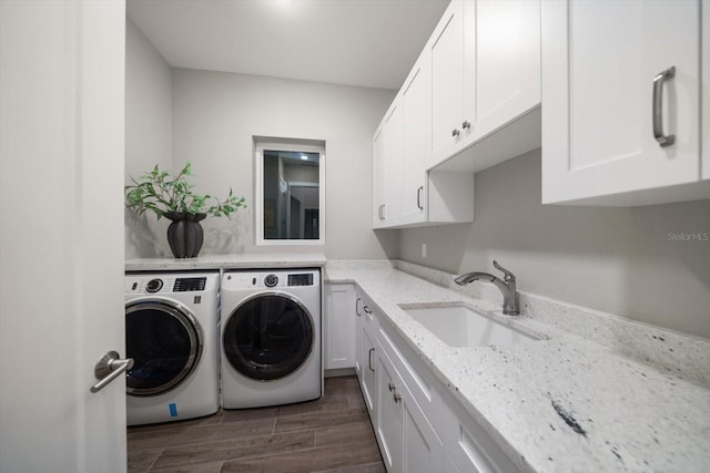 clothes washing area featuring a sink, cabinet space, washing machine and dryer, and dark wood-style flooring