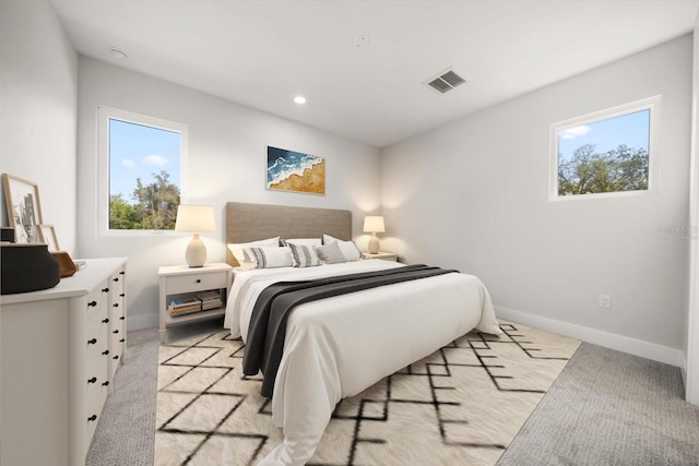 bedroom featuring visible vents, multiple windows, baseboards, and light carpet