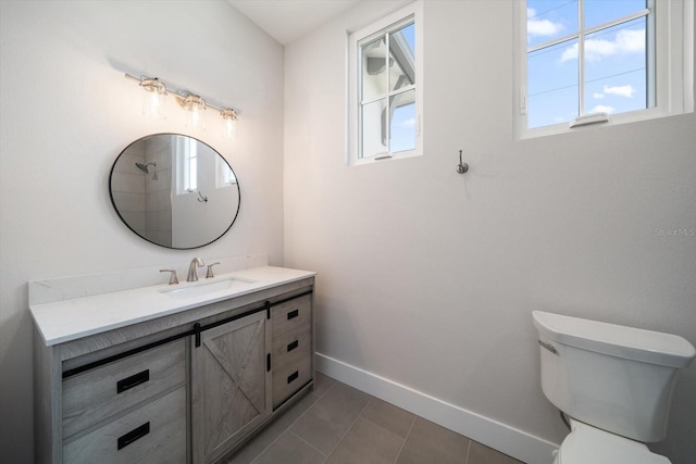 bathroom featuring a wealth of natural light, tile patterned flooring, toilet, and baseboards