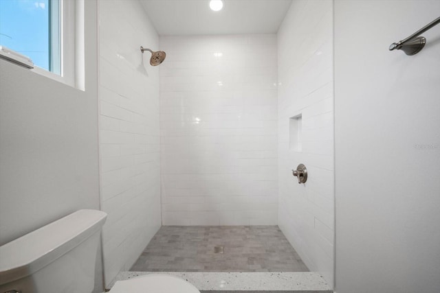 bathroom with toilet and a tile shower