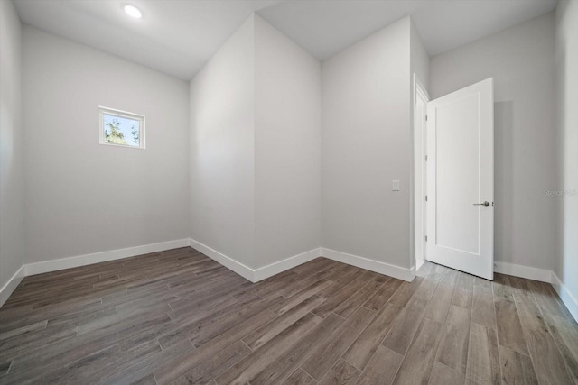 spare room with baseboards and wood finished floors