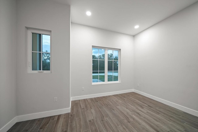 spare room featuring recessed lighting, dark wood-style floors, and baseboards