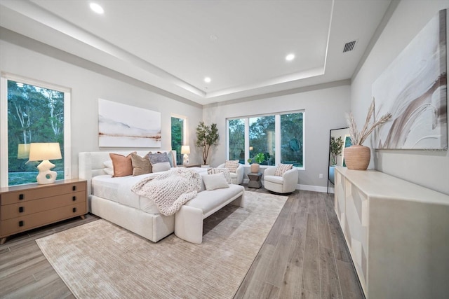 bedroom featuring visible vents, recessed lighting, light wood-style floors, and a tray ceiling