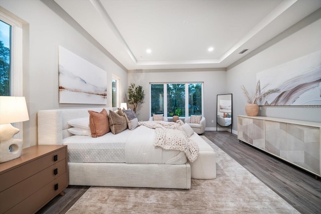 bedroom with visible vents, a raised ceiling, wood finished floors, recessed lighting, and baseboards