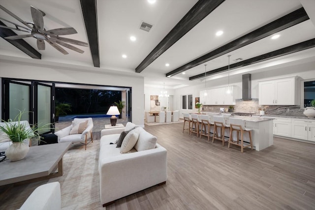 living room with recessed lighting, visible vents, beamed ceiling, and light wood-style flooring