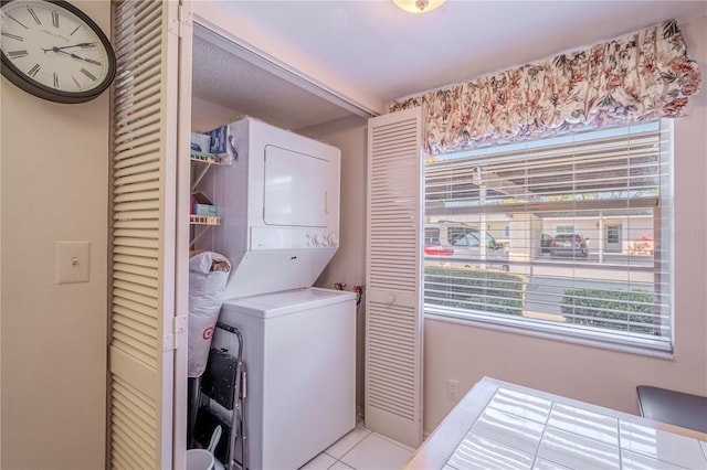 laundry area featuring light tile patterned floors, stacked washer / drying machine, plenty of natural light, and laundry area