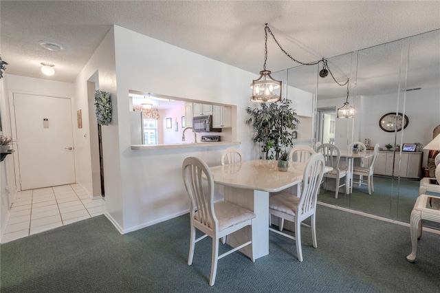 tiled dining space featuring a notable chandelier, a sink, a textured ceiling, and carpet floors