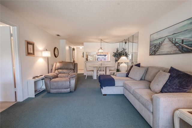 living area featuring visible vents, carpet flooring, and a textured ceiling