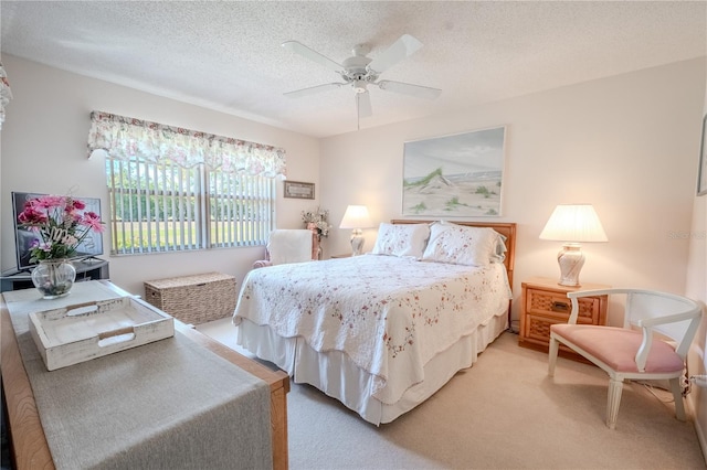 bedroom featuring light colored carpet, a ceiling fan, and a textured ceiling