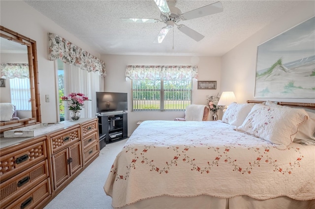 bedroom featuring ceiling fan, light colored carpet, and a textured ceiling