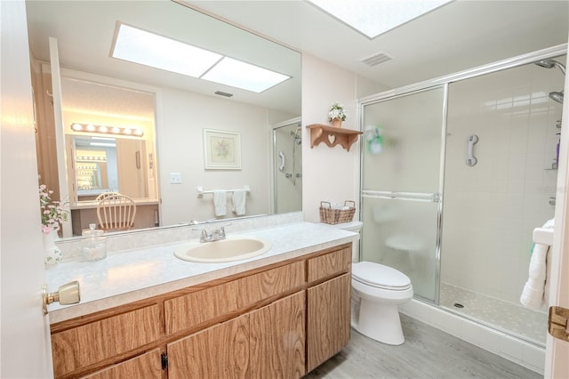 bathroom featuring visible vents, a stall shower, toilet, and vanity