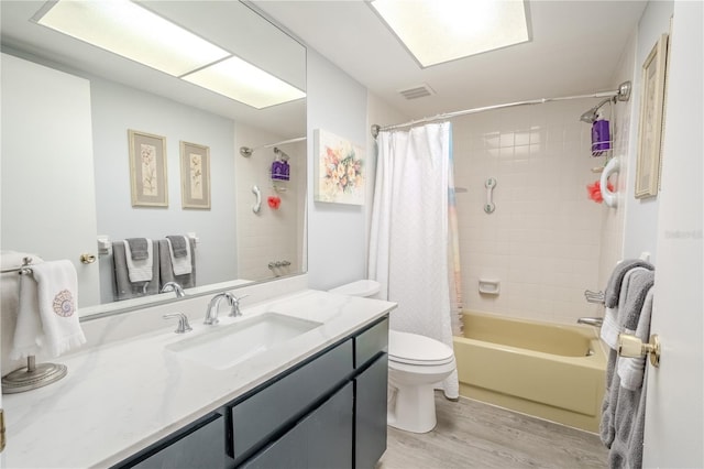 bathroom featuring visible vents, toilet, wood finished floors, vanity, and shower / bathtub combination with curtain