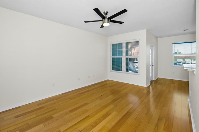 unfurnished room with baseboards, a ceiling fan, and light wood-type flooring