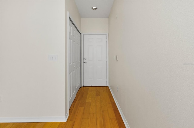 corridor featuring baseboards and light wood-style flooring