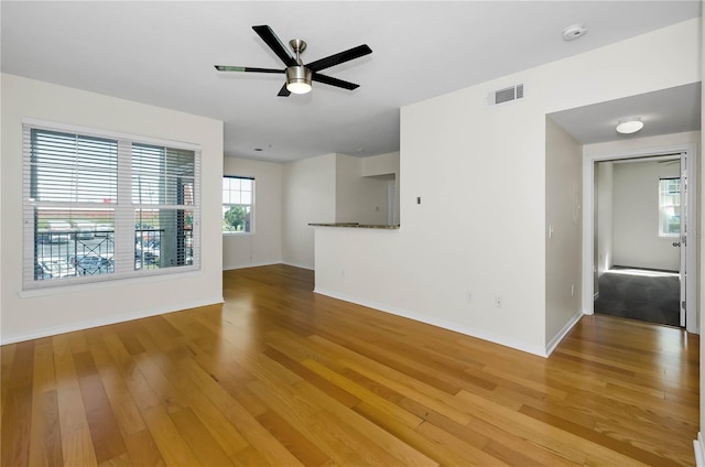 unfurnished living room with baseboards, visible vents, light wood-style flooring, and ceiling fan