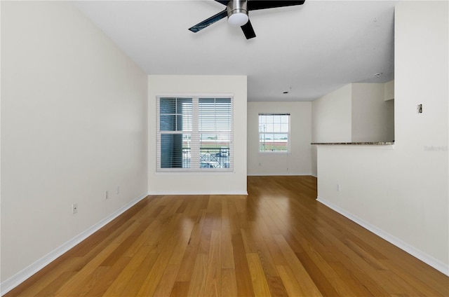 unfurnished room featuring baseboards, a ceiling fan, and light wood-type flooring