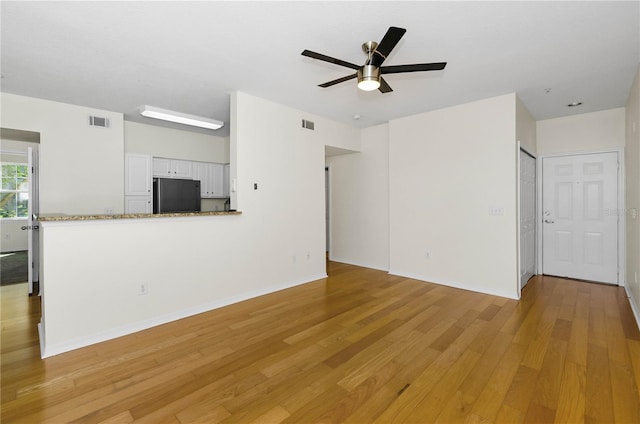 unfurnished living room with light wood-type flooring, baseboards, ceiling fan, and visible vents