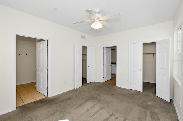 unfurnished bedroom with carpet flooring, tile patterned flooring, ensuite bathroom, baseboards, and visible vents