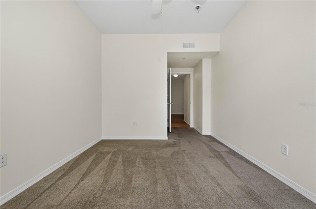 carpeted empty room featuring baseboards, visible vents, and a ceiling fan