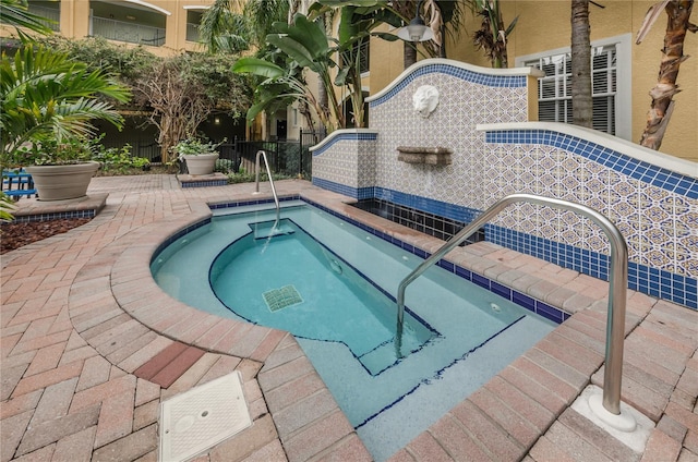 view of swimming pool featuring a community hot tub and fence