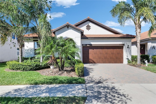 mediterranean / spanish home with stucco siding, a tile roof, decorative driveway, and a garage