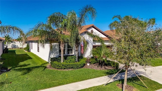 obstructed view of property with an attached garage, a front lawn, a tiled roof, stucco siding, and driveway