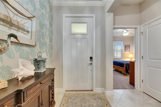 foyer entrance featuring a ceiling fan, light tile patterned flooring, crown molding, wallpapered walls, and baseboards