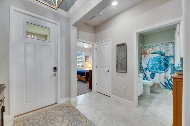 foyer entrance with crown molding, light tile patterned flooring, and baseboards