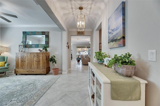 entrance foyer featuring light tile patterned flooring, ceiling fan with notable chandelier, crown molding, and baseboards