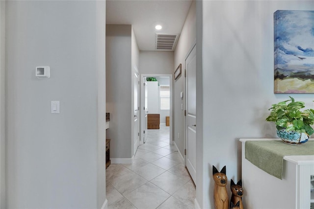 hall featuring light tile patterned floors, visible vents, and baseboards