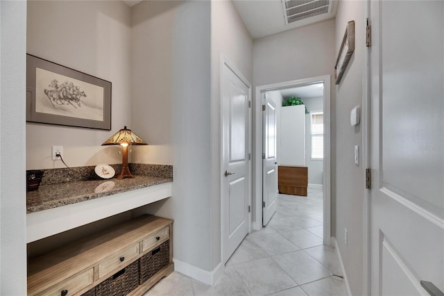 corridor with light tile patterned floors, visible vents, and baseboards