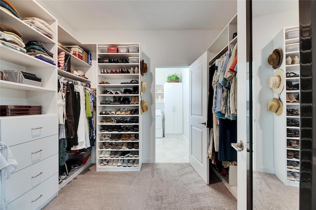 walk in closet with washer / clothes dryer and carpet flooring