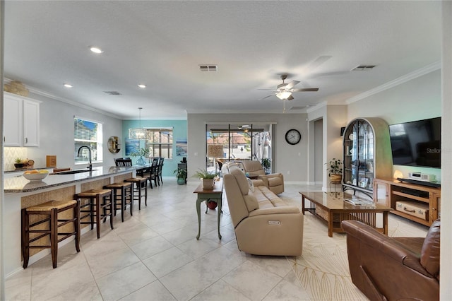 living area with visible vents, plenty of natural light, and ceiling fan with notable chandelier