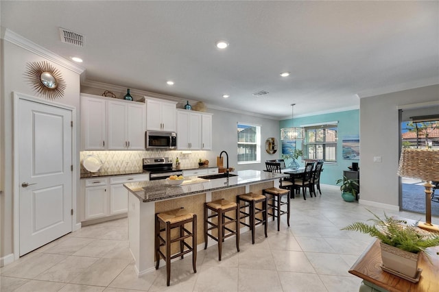 kitchen featuring a kitchen bar, visible vents, a sink, tasteful backsplash, and stainless steel appliances