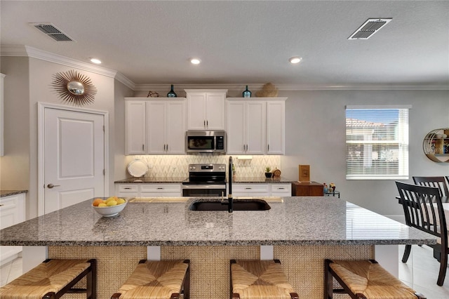 kitchen featuring tasteful backsplash, visible vents, appliances with stainless steel finishes, and a sink