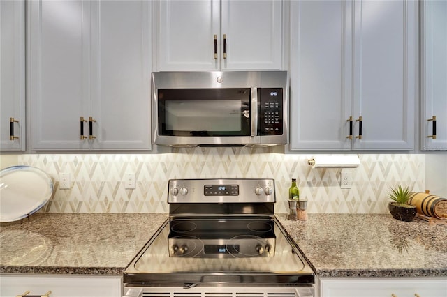 kitchen featuring light stone counters, backsplash, appliances with stainless steel finishes, and white cabinets