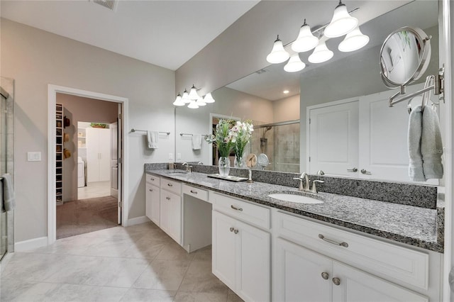 full bath with double vanity, a shower stall, a walk in closet, and a sink