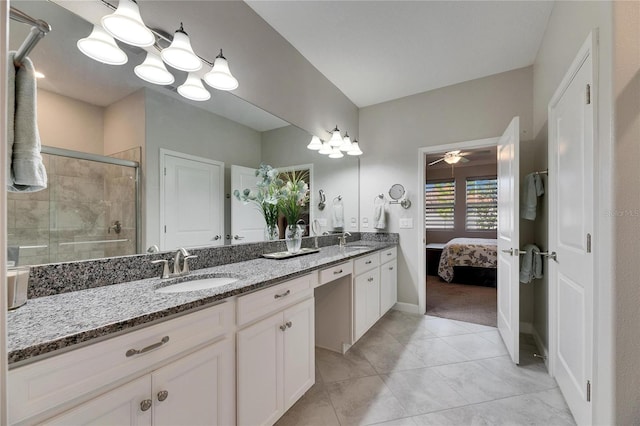 ensuite bathroom featuring a shower stall, double vanity, tile patterned floors, and a sink