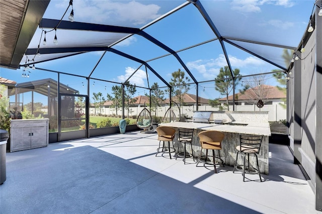 view of patio featuring outdoor wet bar, area for grilling, a lanai, and fence